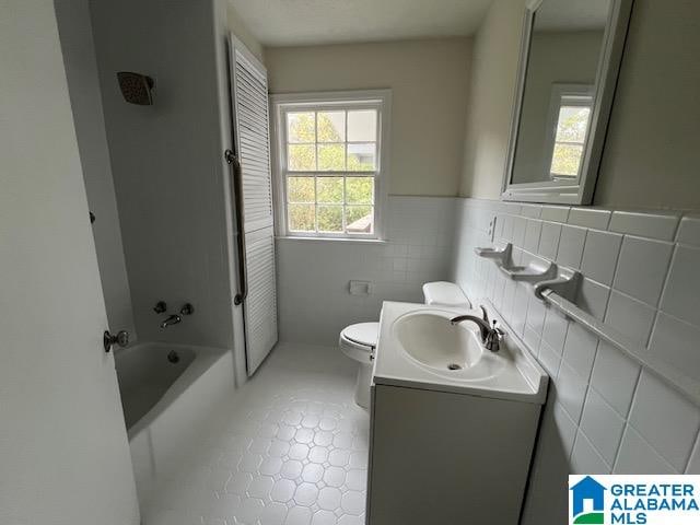 bathroom with tile walls, vanity, toilet, and tile patterned floors