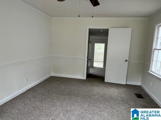 carpeted empty room with ceiling fan, crown molding, and a wealth of natural light