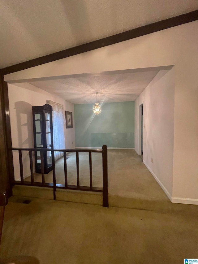 unfurnished room featuring a notable chandelier, lofted ceiling with beams, and carpet