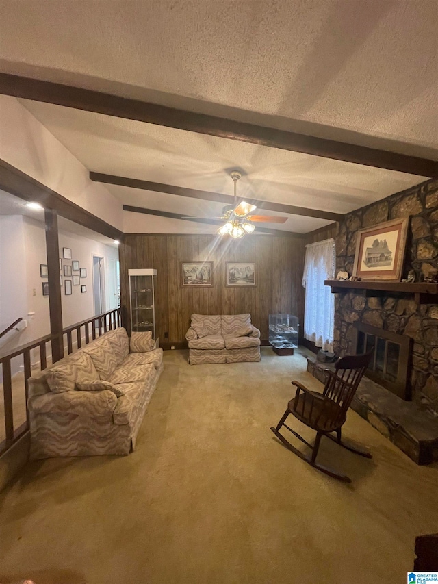 living room featuring wood walls, vaulted ceiling with beams, a stone fireplace, a textured ceiling, and carpet floors