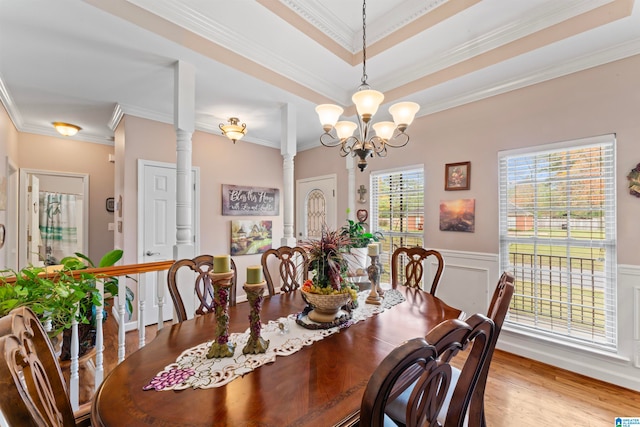 dining area featuring ornate columns, ornamental molding, a chandelier, and wood-type flooring