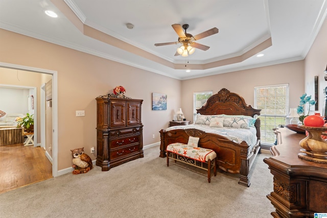 carpeted bedroom featuring ceiling fan, multiple windows, a tray ceiling, and ornamental molding