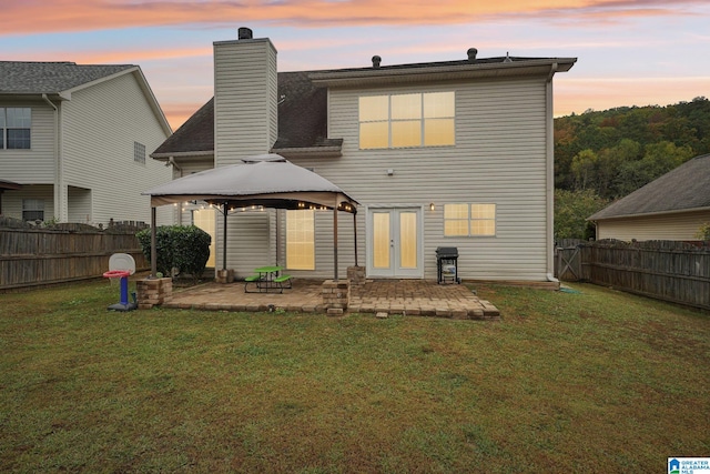 back house at dusk with a yard, a patio area, and a gazebo