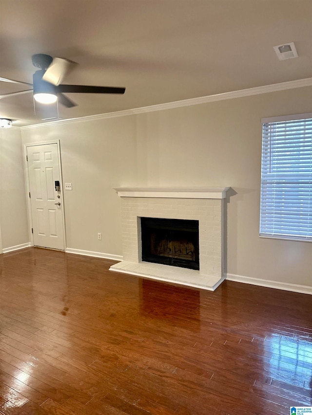 unfurnished living room with ceiling fan, ornamental molding, dark hardwood / wood-style flooring, and a fireplace