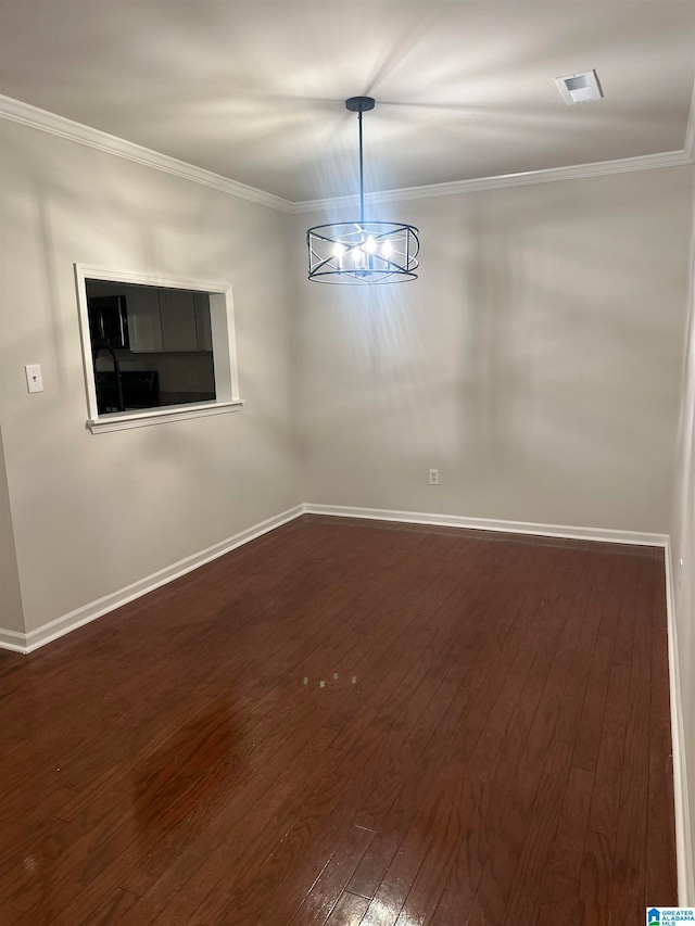 spare room featuring dark wood-type flooring, crown molding, and an inviting chandelier