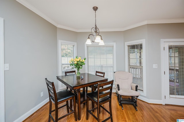 dining area with wood-type flooring, ornamental molding, and an inviting chandelier