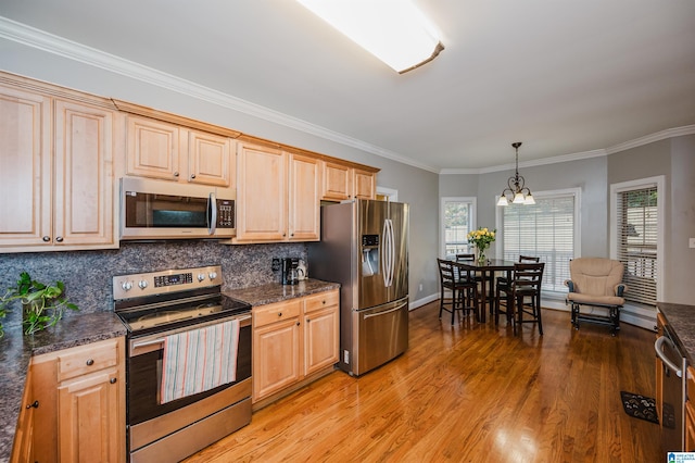 kitchen featuring a notable chandelier, crown molding, stainless steel appliances, and hanging light fixtures