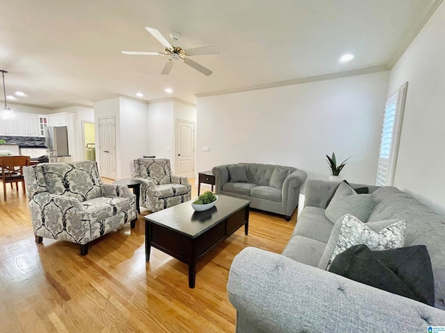 living room featuring ornamental molding, light hardwood / wood-style floors, and ceiling fan