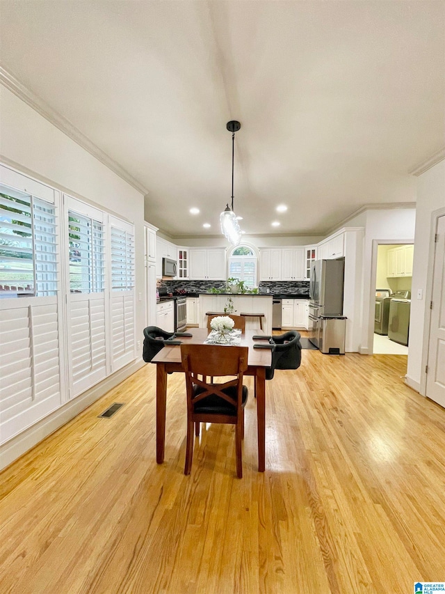 dining room featuring ornamental molding, light hardwood / wood-style flooring, and independent washer and dryer