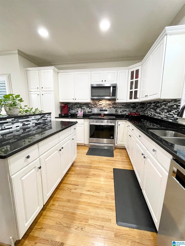 kitchen featuring decorative backsplash, white cabinetry, sink, light hardwood / wood-style floors, and stainless steel appliances