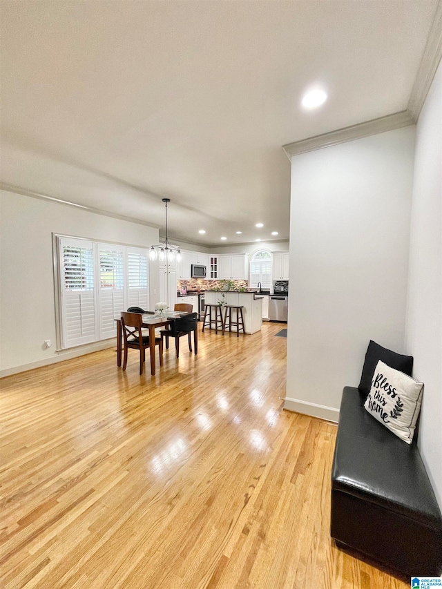 dining area featuring light hardwood / wood-style floors, an inviting chandelier, and crown molding