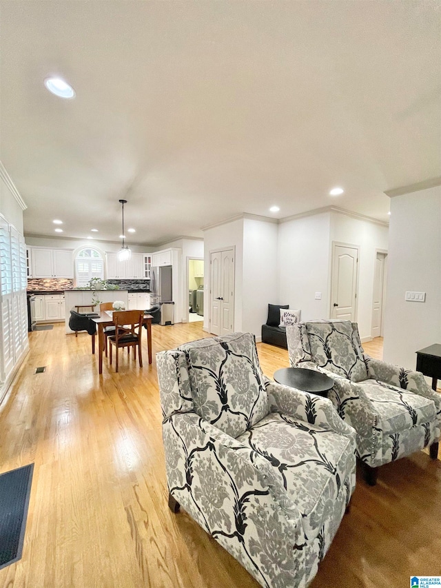 living room with crown molding and light wood-type flooring