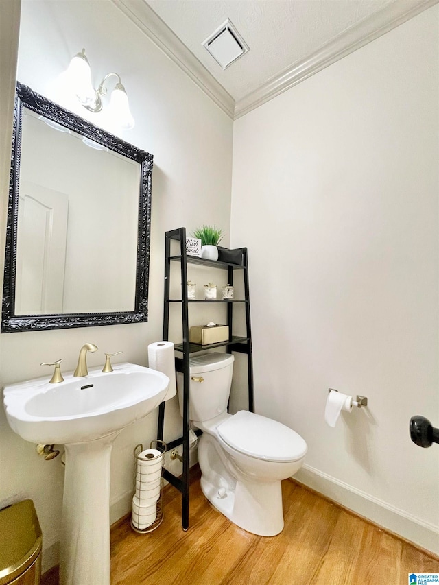 bathroom with toilet, crown molding, wood-type flooring, and sink