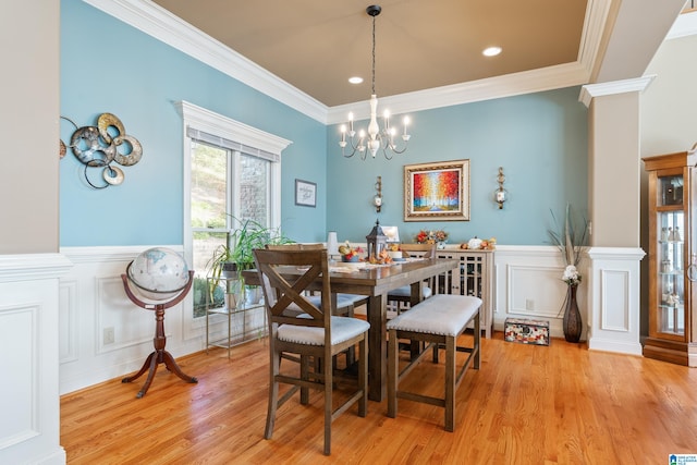 dining room featuring decorative columns, light hardwood / wood-style flooring, and crown molding