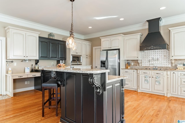 kitchen with custom exhaust hood, an island with sink, light hardwood / wood-style flooring, and stainless steel appliances