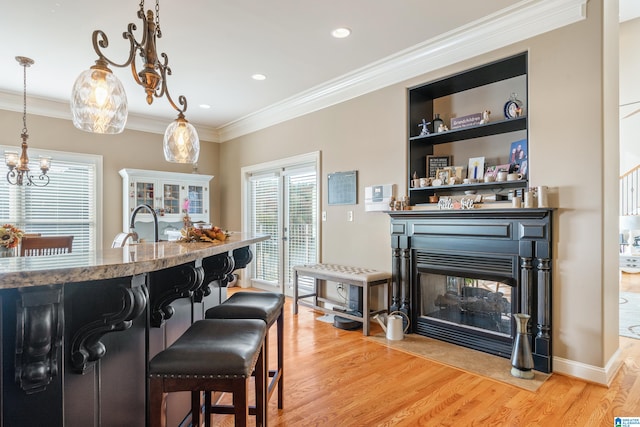 kitchen featuring light hardwood / wood-style floors, ornamental molding, a kitchen breakfast bar, and pendant lighting