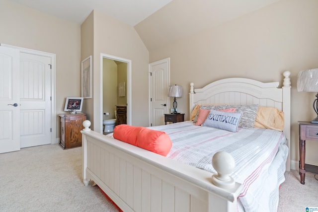 bedroom with lofted ceiling, light colored carpet, and ensuite bath