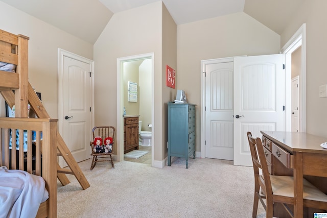 bedroom with ensuite bathroom, vaulted ceiling, and light colored carpet