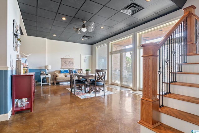 dining area featuring ornate columns, a drop ceiling, and concrete floors