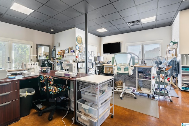 office space featuring concrete floors, a healthy amount of sunlight, and a paneled ceiling