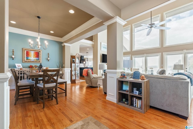 dining area featuring light hardwood / wood-style floors, ornate columns, ceiling fan with notable chandelier, crown molding, and a towering ceiling