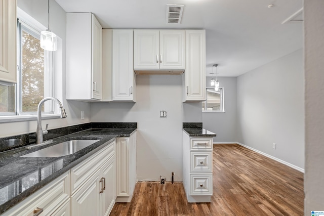 kitchen featuring sink, white cabinetry, decorative light fixtures, and a healthy amount of sunlight