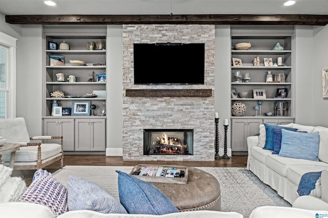 living room with beamed ceiling, dark wood-type flooring, a fireplace, and built in features