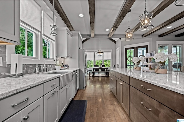 kitchen featuring beam ceiling, dark wood-type flooring, appliances with stainless steel finishes, and decorative light fixtures