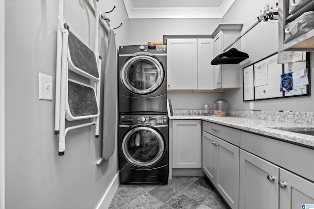 laundry area featuring crown molding, cabinets, and stacked washer and clothes dryer