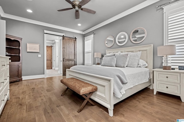 bedroom with light wood-type flooring, a barn door, ceiling fan, connected bathroom, and ornamental molding