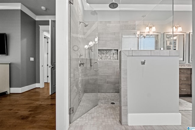 bathroom featuring wood-type flooring, ornamental molding, a shower with shower door, vanity, and a notable chandelier