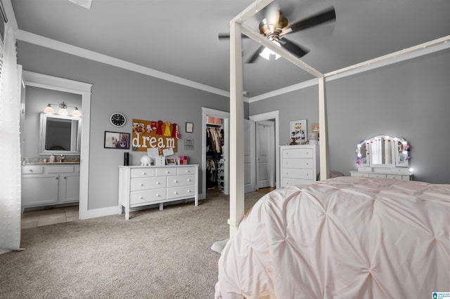 carpeted bedroom with a spacious closet, a closet, ceiling fan, connected bathroom, and crown molding