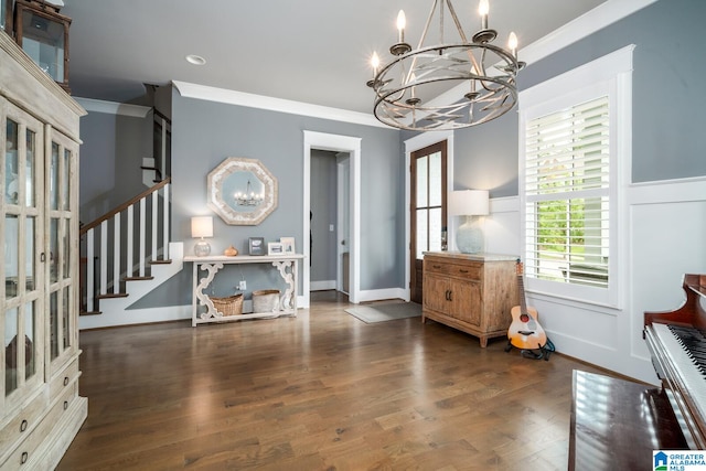 foyer entrance with dark wood-type flooring, crown molding, and an inviting chandelier