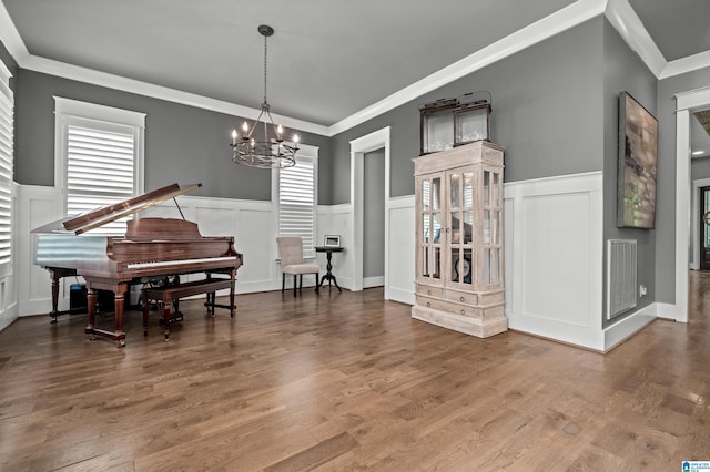 living area featuring crown molding, a notable chandelier, and hardwood / wood-style flooring