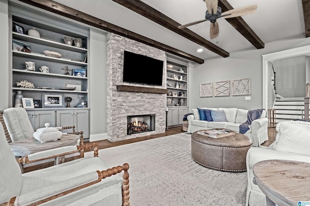 living room featuring beam ceiling, hardwood / wood-style flooring, a fireplace, and built in shelves