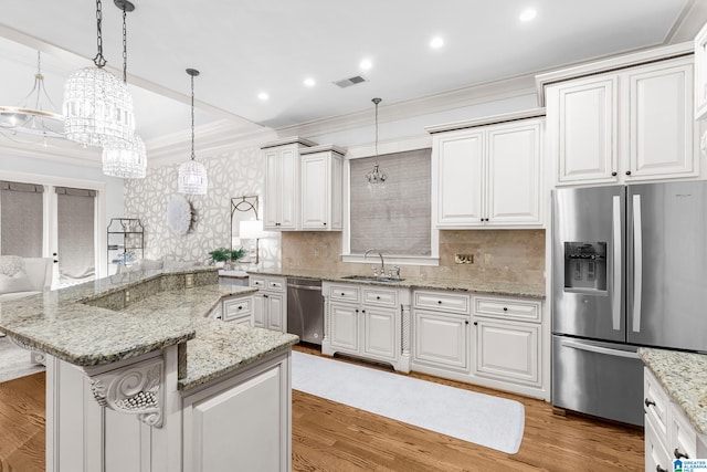 kitchen with white cabinets, appliances with stainless steel finishes, hardwood / wood-style floors, and hanging light fixtures