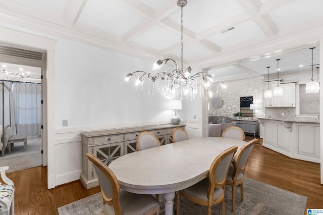 dining room with a chandelier, ornamental molding, dark hardwood / wood-style floors, beamed ceiling, and coffered ceiling