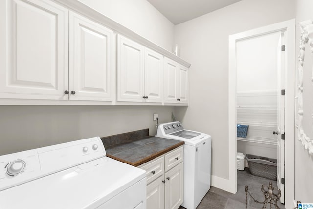 clothes washing area with washer and clothes dryer, light tile patterned floors, and cabinets