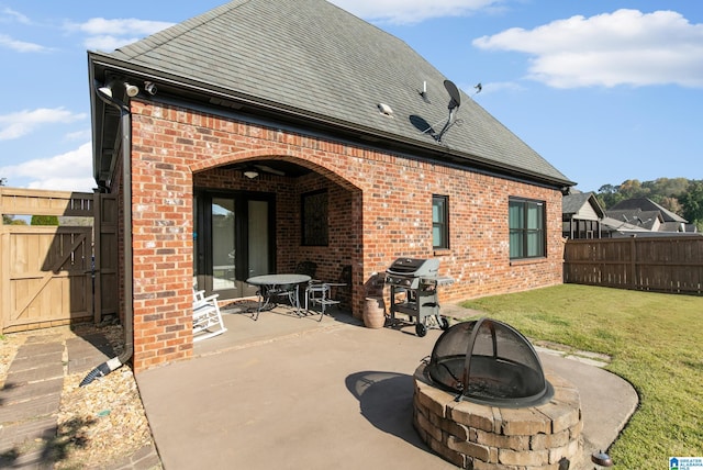 rear view of house with a patio, an outdoor fire pit, and a yard