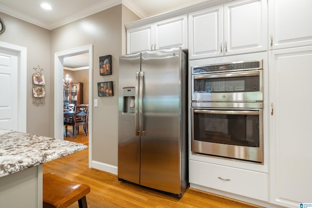 kitchen featuring crown molding, light stone countertops, white cabinets, light wood-type flooring, and appliances with stainless steel finishes