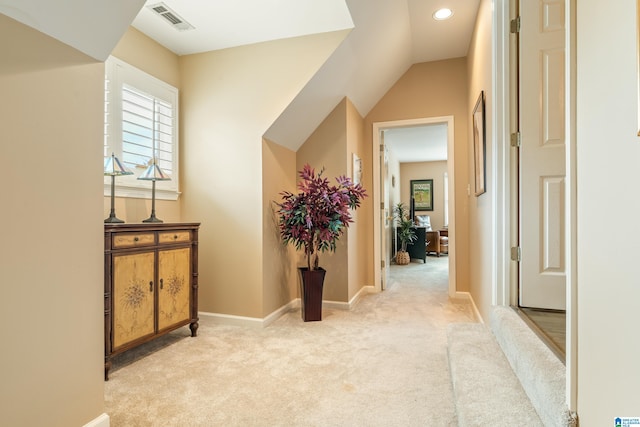 hall featuring vaulted ceiling and light colored carpet