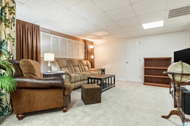 living room featuring carpet floors and a paneled ceiling