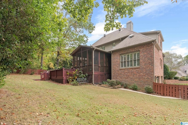 rear view of property featuring a yard, a deck, and a sunroom