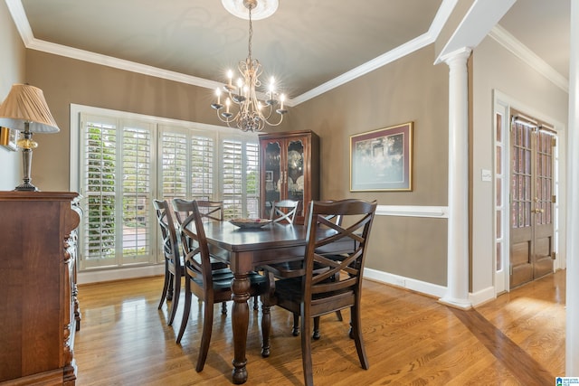 dining space featuring crown molding, decorative columns, a chandelier, and light wood-type flooring