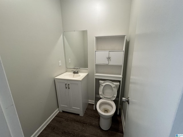bathroom with wood finished floors, vanity, toilet, and baseboards