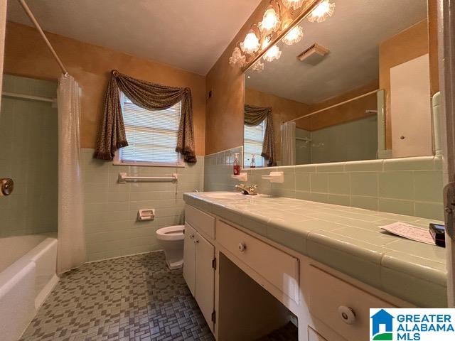 full bathroom with toilet, shower / bath combo with shower curtain, vanity, and tile walls