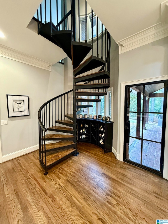 stairs with ornamental molding, baseboards, and wood finished floors