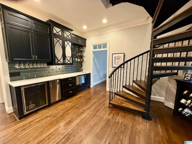 bar with a dry bar, light wood finished floors, beverage cooler, and decorative backsplash