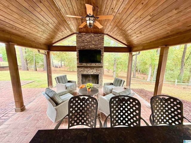 view of patio with a ceiling fan, fence, and an outdoor living space with a fireplace