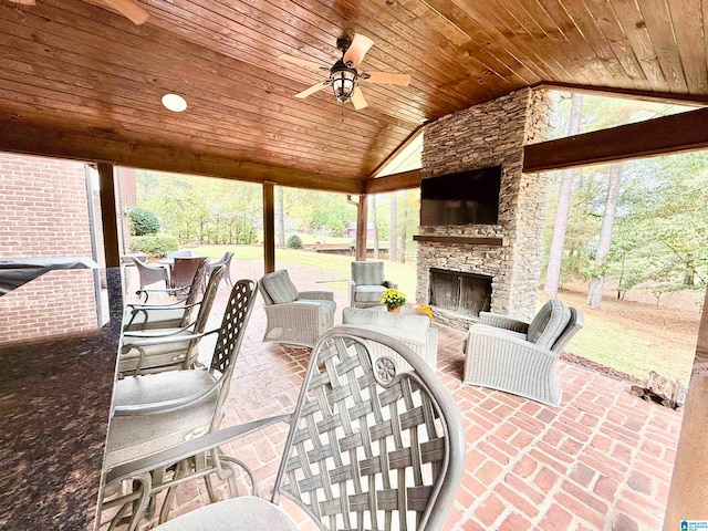 view of patio / terrace with outdoor dining space, an outdoor stone fireplace, and a ceiling fan